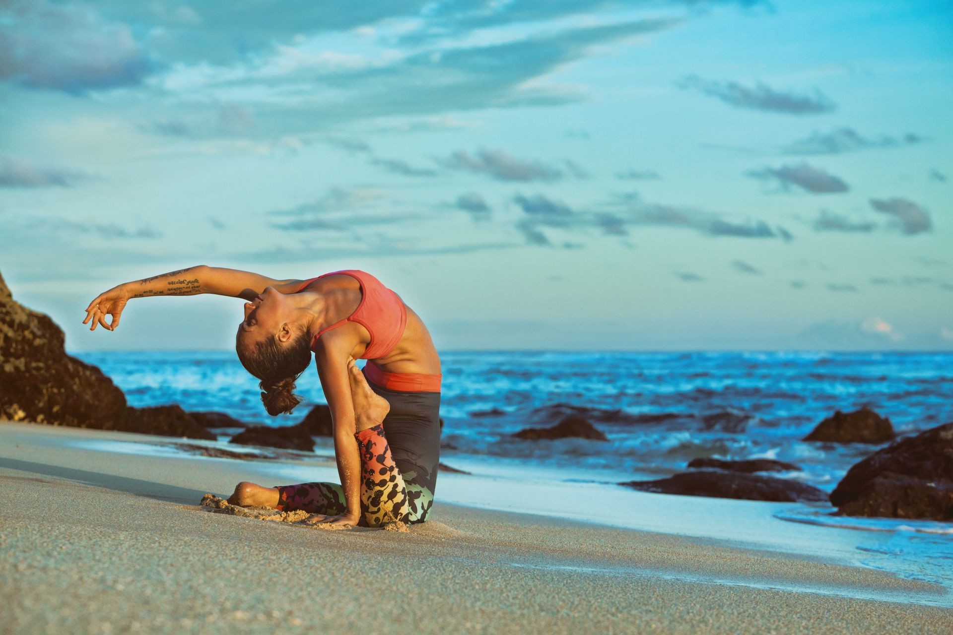 Young active woman sit in yoga pose on sand beach, stretching to keep fit and health. 